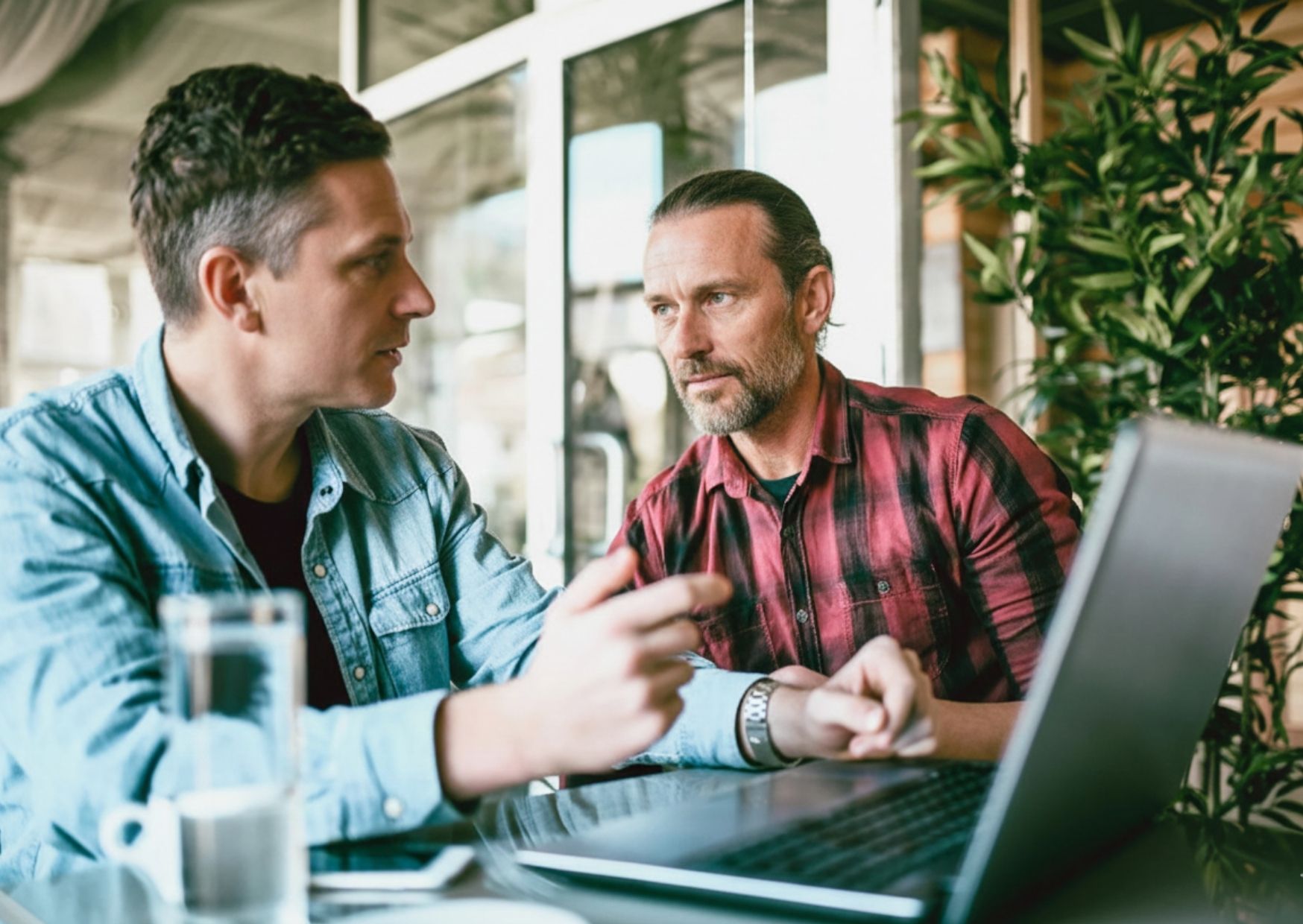 Two friends in real conversation at a table — what it looks like to stay a friend even when someone isn't interested in faith