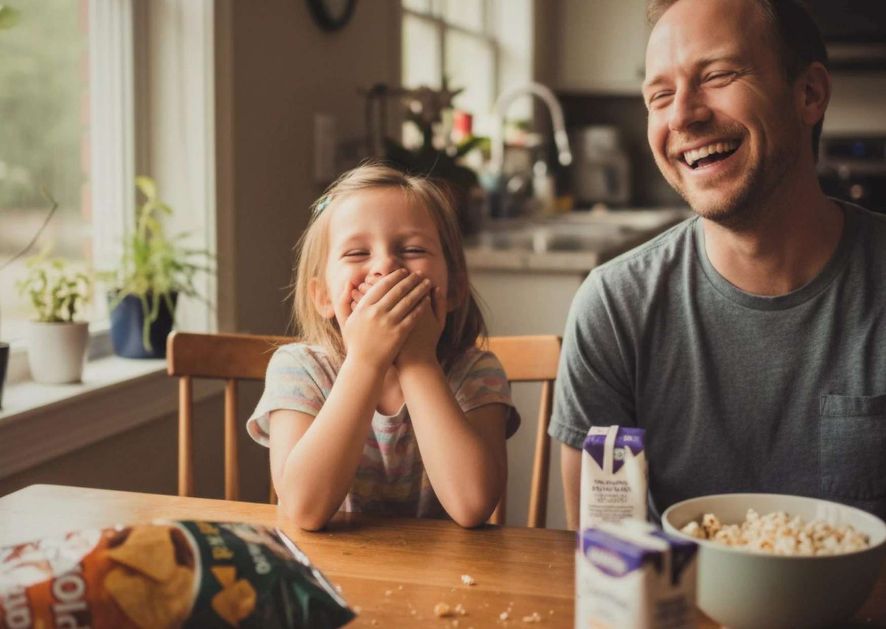 Parent and child laughing together at kitchen table